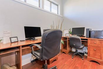 A room with a desk, chairs, and computers.
