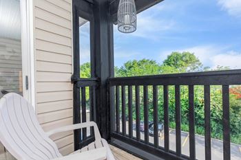 A white chair is on a porch with a black railing.
