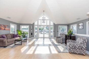 A spacious living room with a high ceiling and natural light streaming in through the windows.