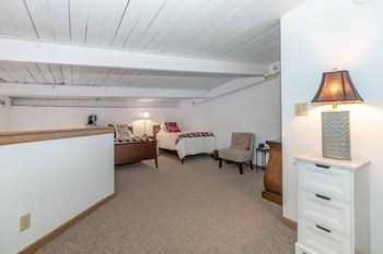 A bedroom with a bed, chair, and lamp.