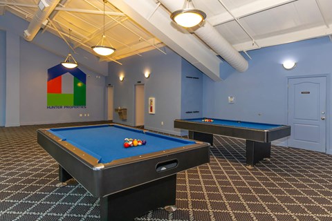 A pool table with a blue cloth and a pool table with a brown cloth.