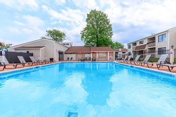 A swimming pool in a residential area with a blue sky and clouds.