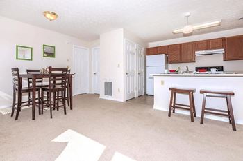 A kitchen with white appliances and brown wooden bar stools.