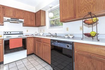 A kitchen with wooden cabinets and a black dishwasher.