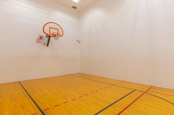 A basketball hoop is mounted on a wall in a room with a wooden floor.