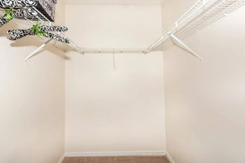 A white closet with a hanging shelf and a hanger.