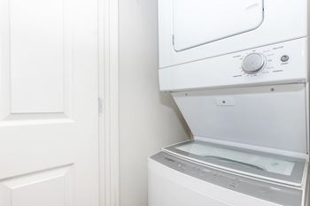 A white dryer is on the wall next to a white door.