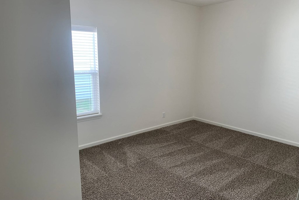 a small empty room with a window and a carpeted floor