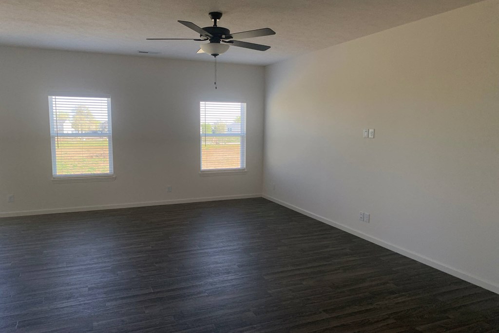 an empty room with a ceiling fan and three windows