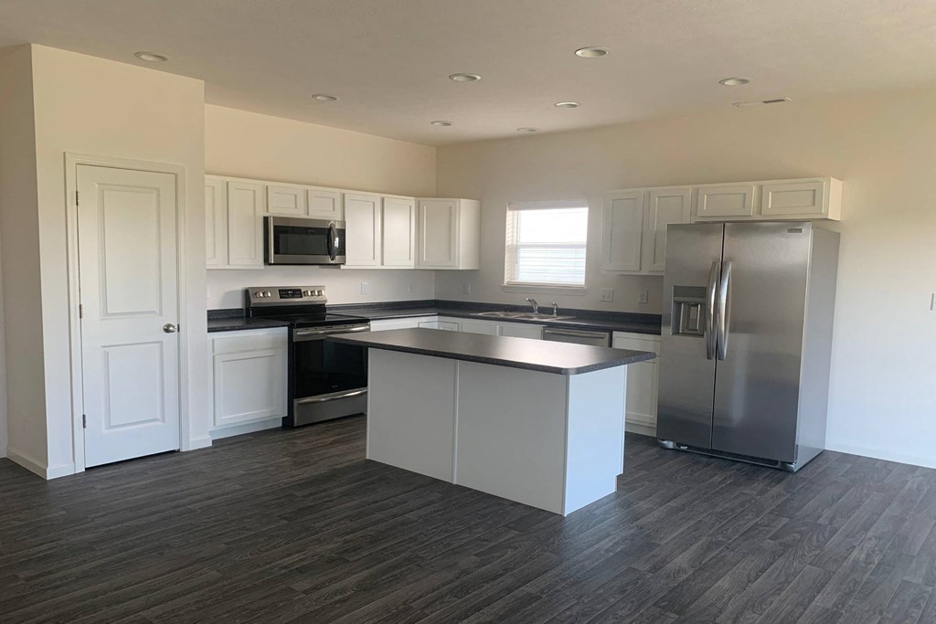a kitchen with white cabinets and a black counter top