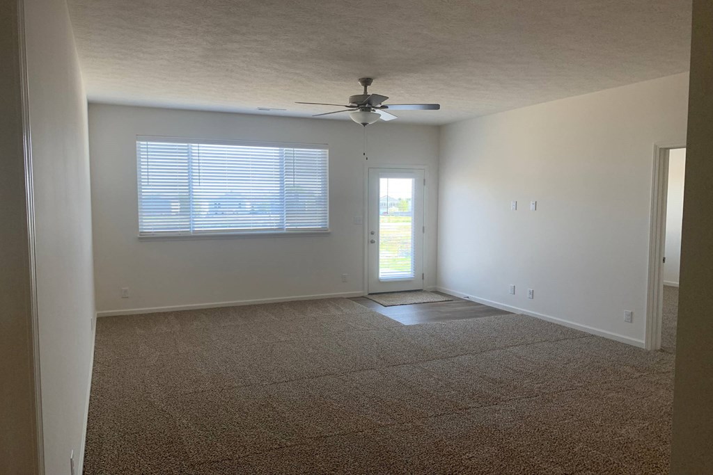 an empty room with a ceiling fan and a window