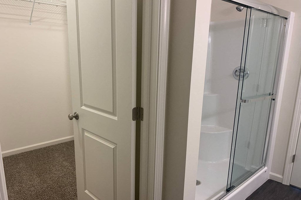 a bathroom with a white door and a glass shower stall