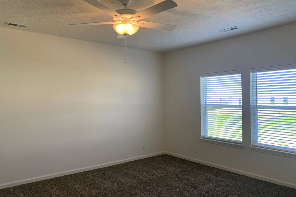 a bedroom with two windows and a ceiling fan