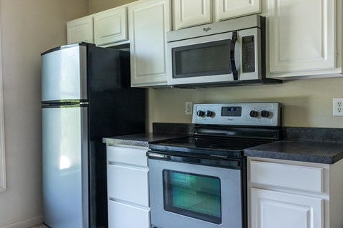 a kitchen with white cabinets and black appliances and a refrigerator