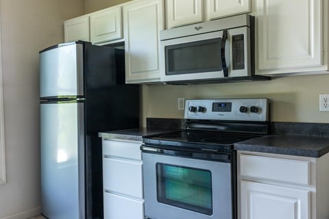 a kitchen with white cabinets and black appliances and a refrigerator