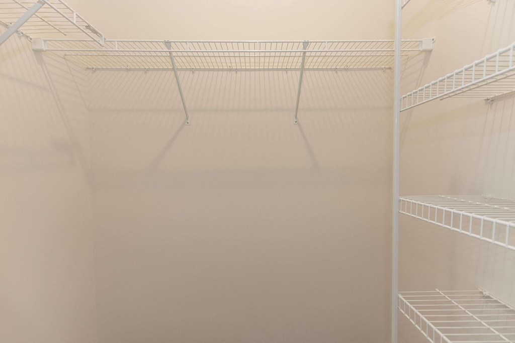 a walk in closet with white shelving