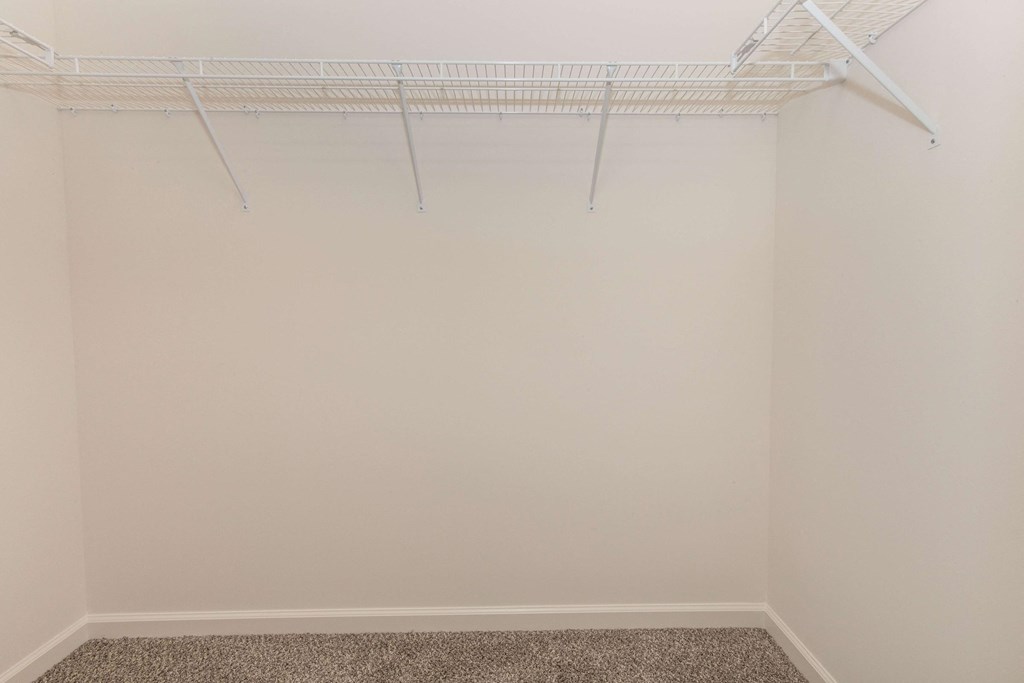 a bedroom with a white closet and a white shelf on the wall
