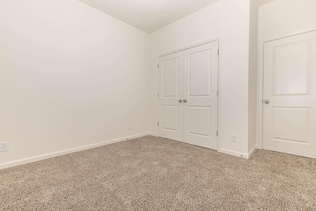 a bedroom with two doors and a carpeted floor