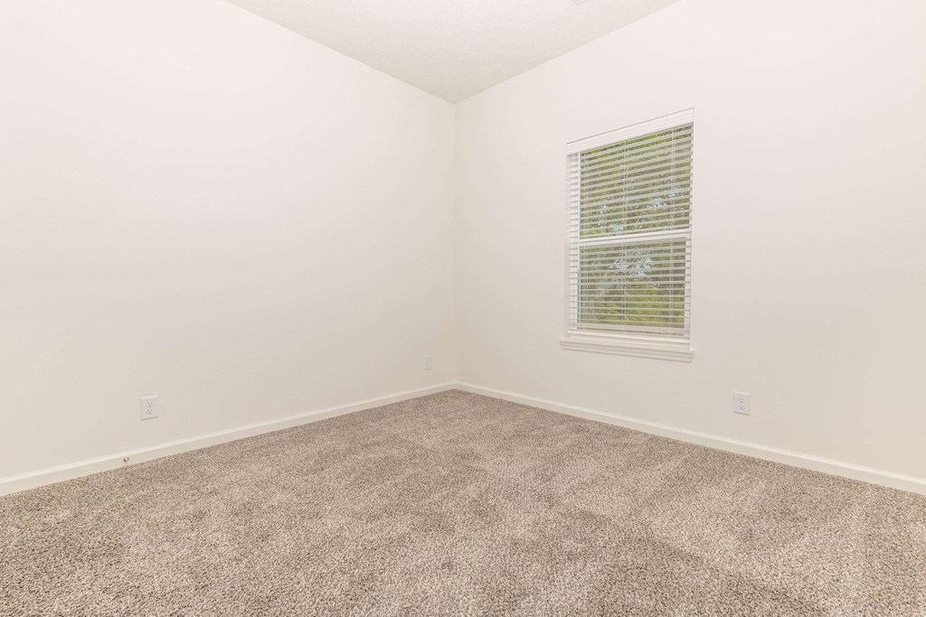 a bedroom with white walls and carpet