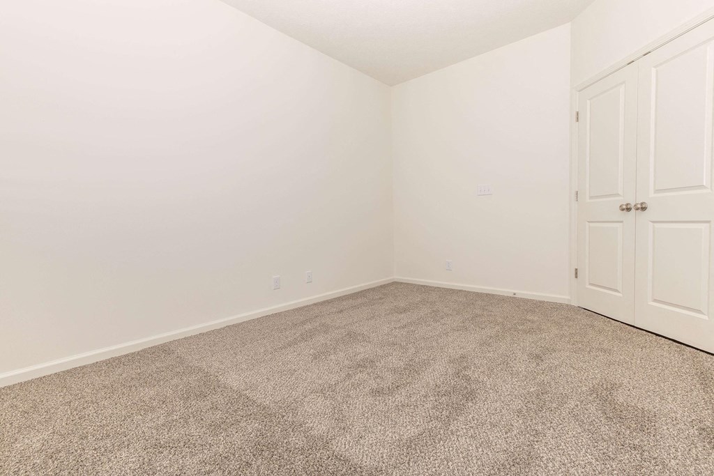 a bedroom with white walls and carpet