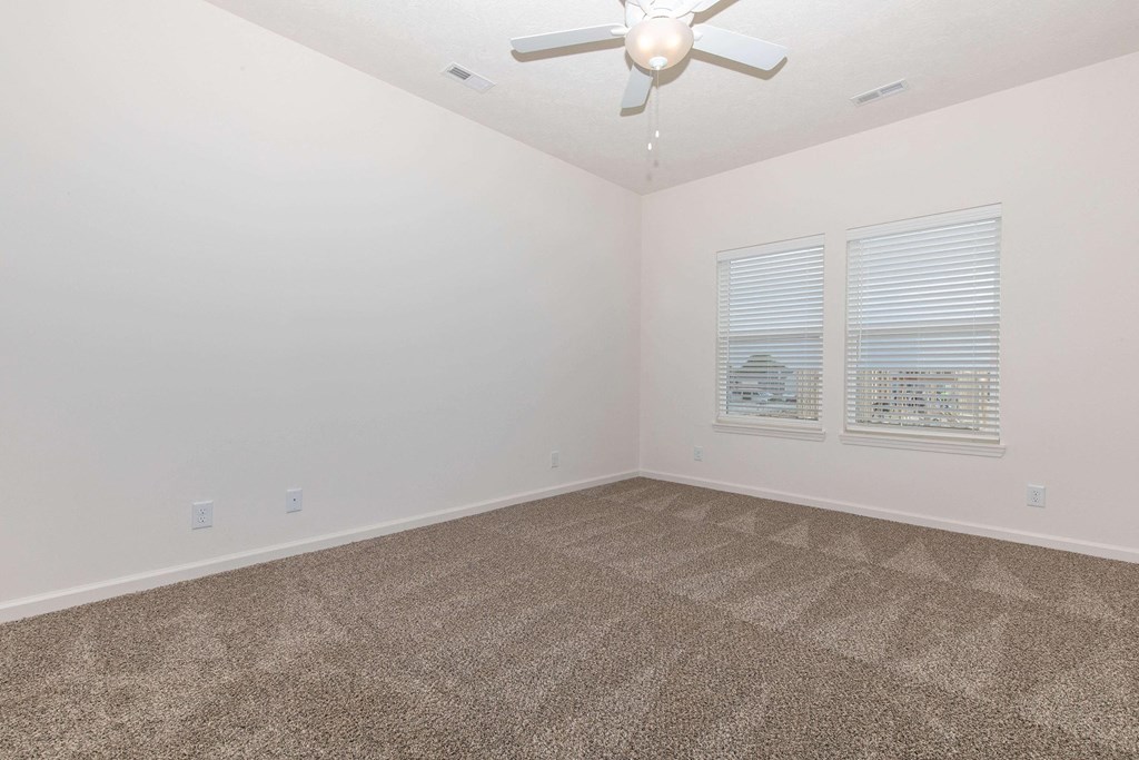 a bedroom with a ceiling fan and two windows