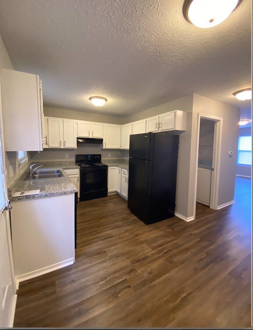 A kitchen with black appliances and white cabinets.