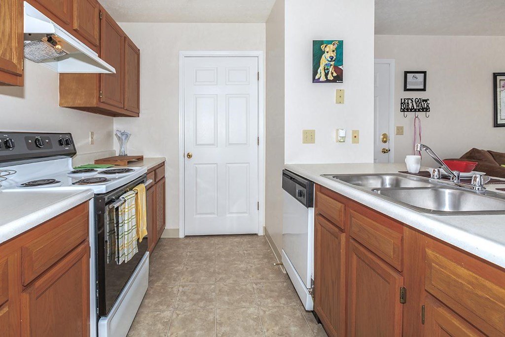 A kitchen with a white door and brown cabinets.