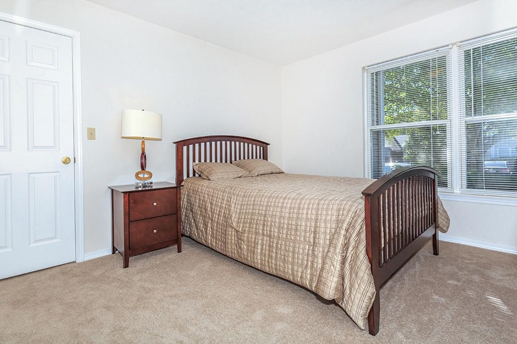 A bedroom with a bed, nightstand, and window.