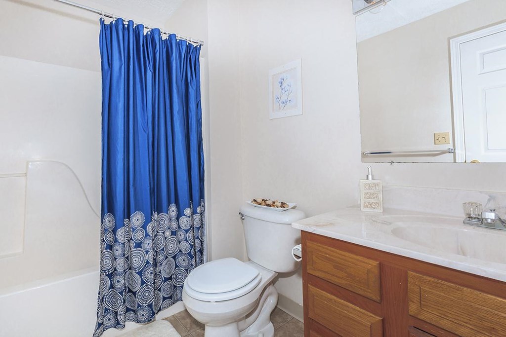 A white toilet with a blue shower curtain in a bathroom.