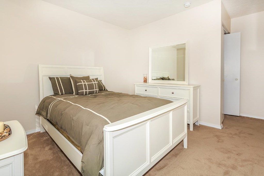 A bedroom with a bed, dresser, and mirror.