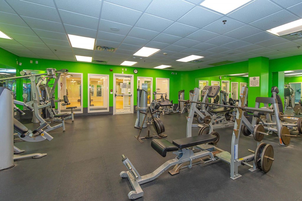 A gym with a variety of equipment including treadmills, weights, and exercise machines.