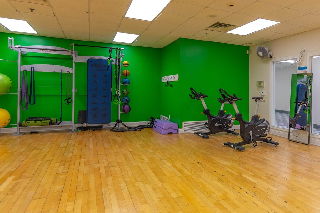 A gym with a green wall and wooden floor.