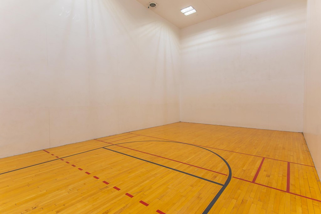 A squash court with a yellow floor and white walls.