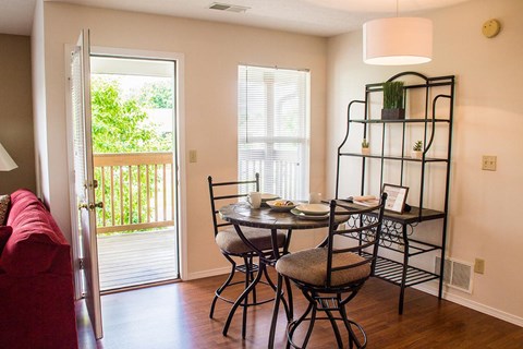 A dining room with a table set for two and a red couch.
