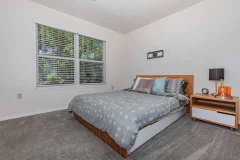 A bedroom with a bed, nightstand, and window.