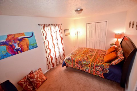 A bedroom with a bed, pillows, and a painting on the wall.