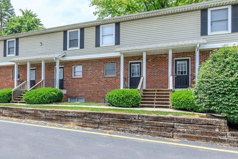 A row of red brick houses with white trim and black shutters.