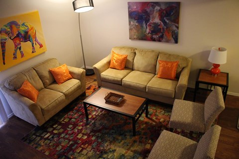 A living room with a couch, chair, and a painting on the wall.