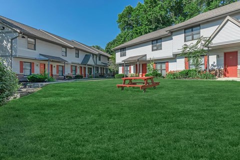 A grassy area in front of a building with a picnic table.