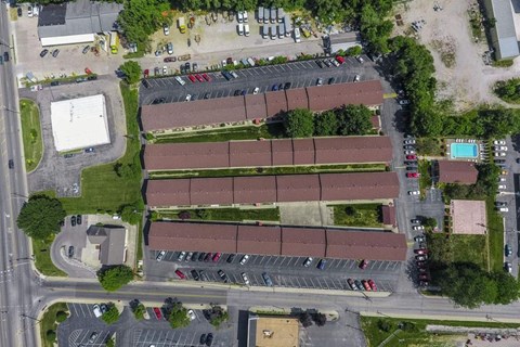 An aerial view of a parking lot with a building and a pool.