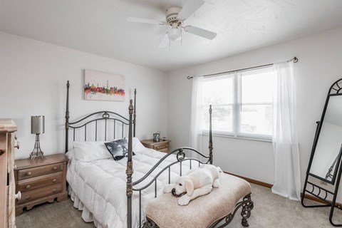A bedroom with a four poster bed and a dog on the foot of the bed.