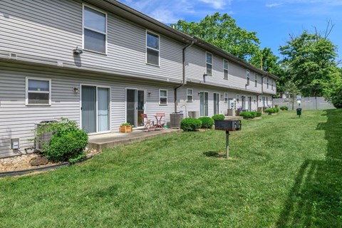 A row of houses with green lawns and trees in the background.