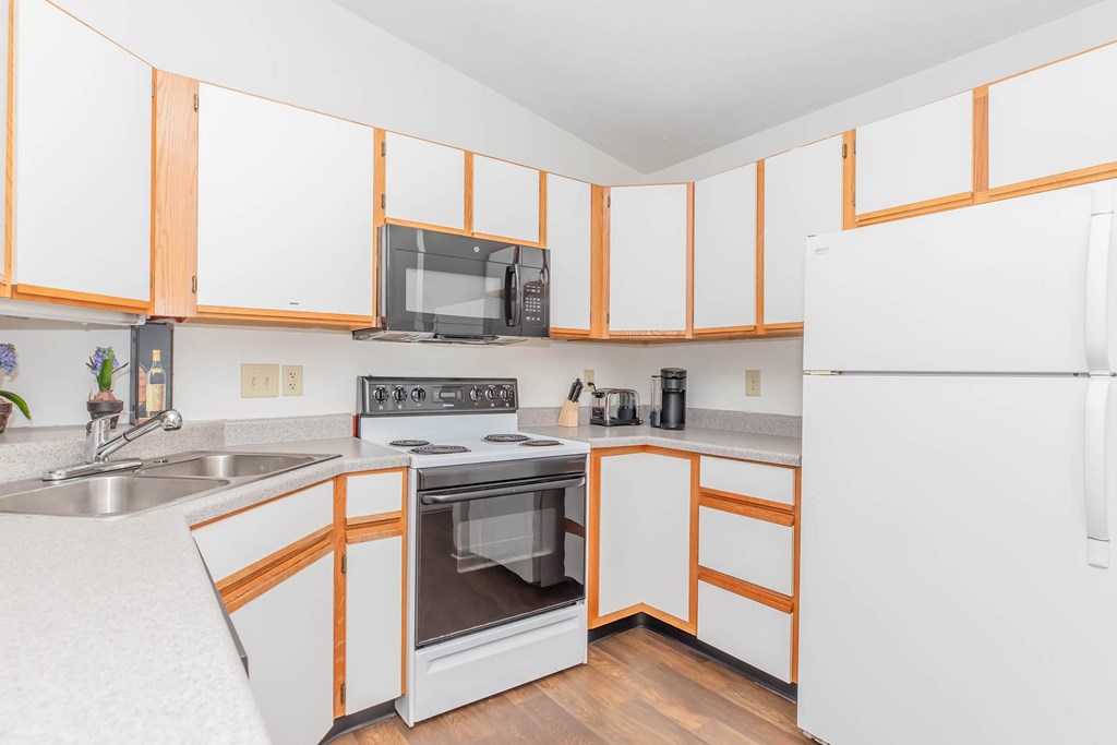 A kitchen with white cabinets and a white refrigerator.