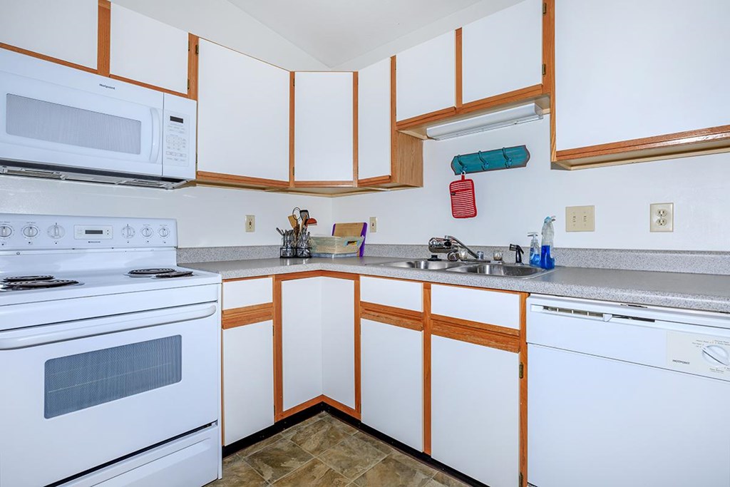 A kitchen with white appliances and wooden cabinets.