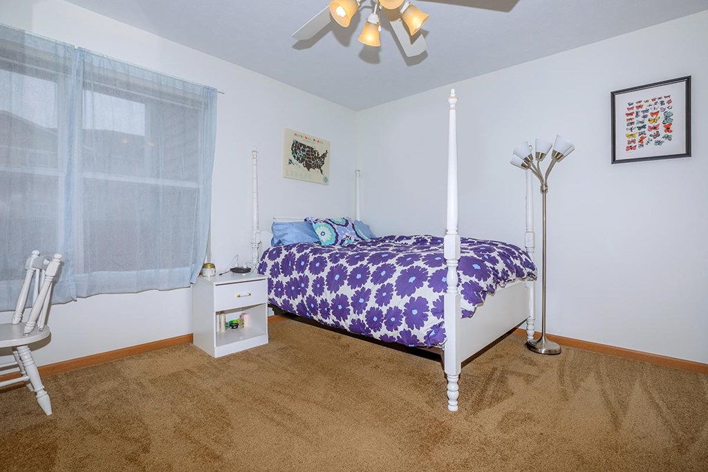 A bedroom with a bed, nightstand, and chair.