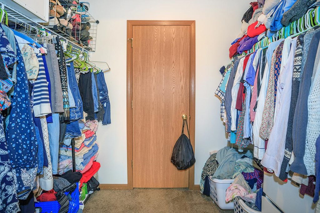 A room with a door and clothes hanging on a rack.
