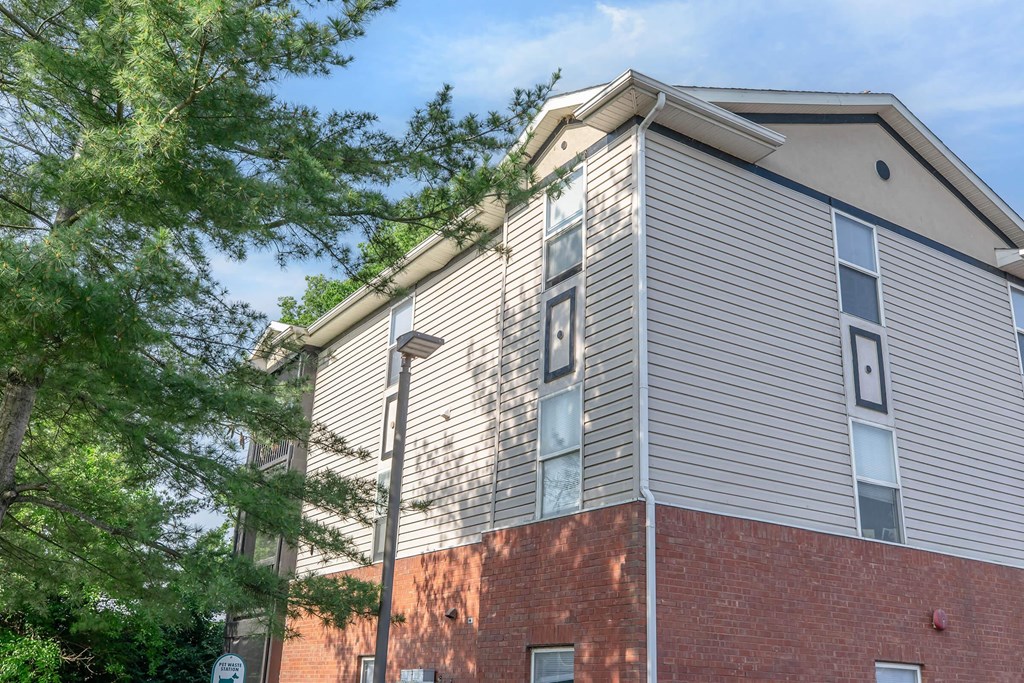 A building with a red brick base and a grey siding upper half.