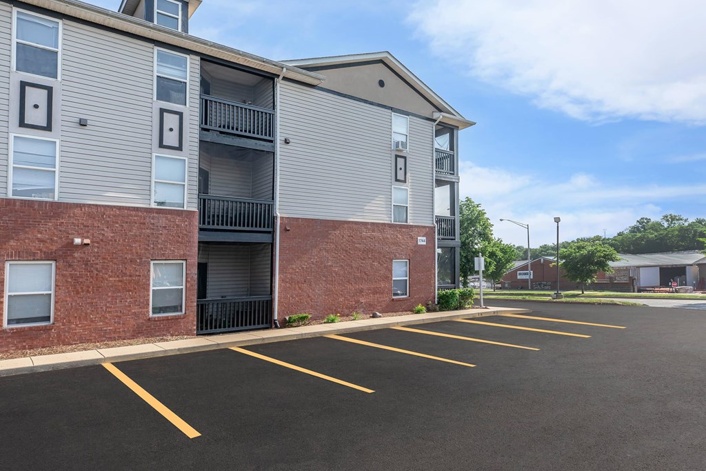A parking lot in front of a multi-story apartment building.