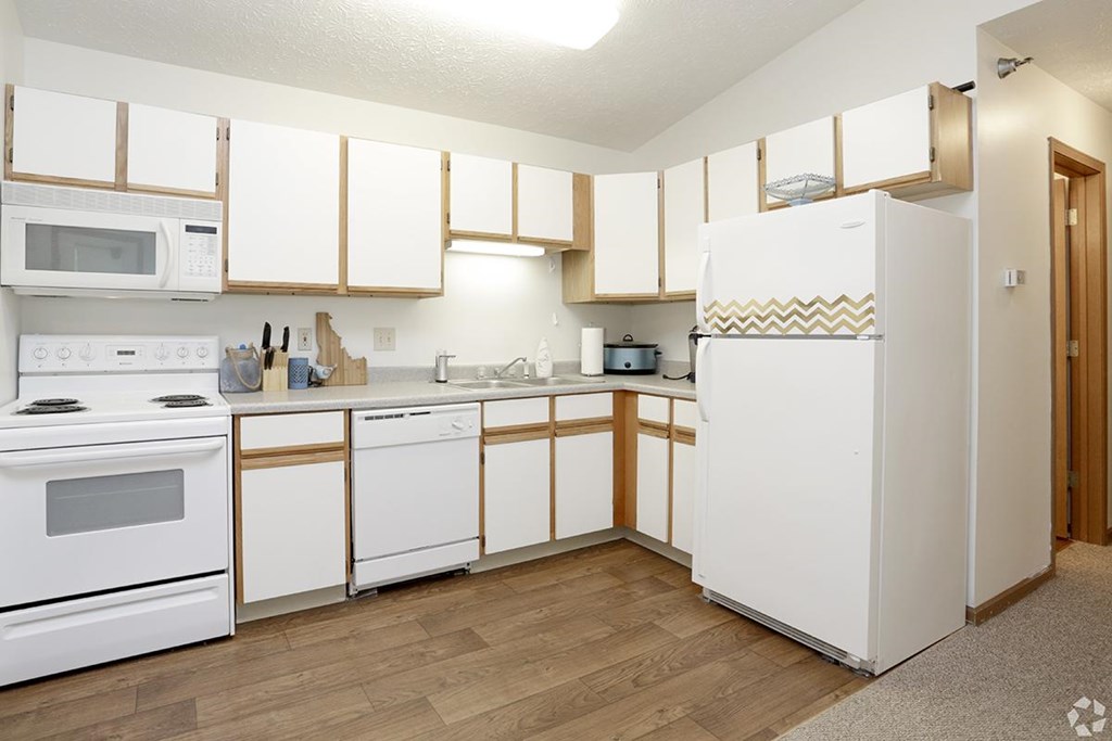 A kitchen with white appliances and wooden cabinets.