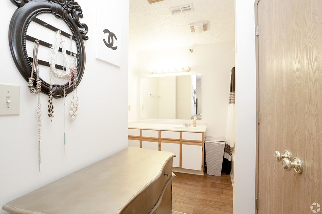 A bathroom with a mirror, a wooden vanity, and a wooden door.